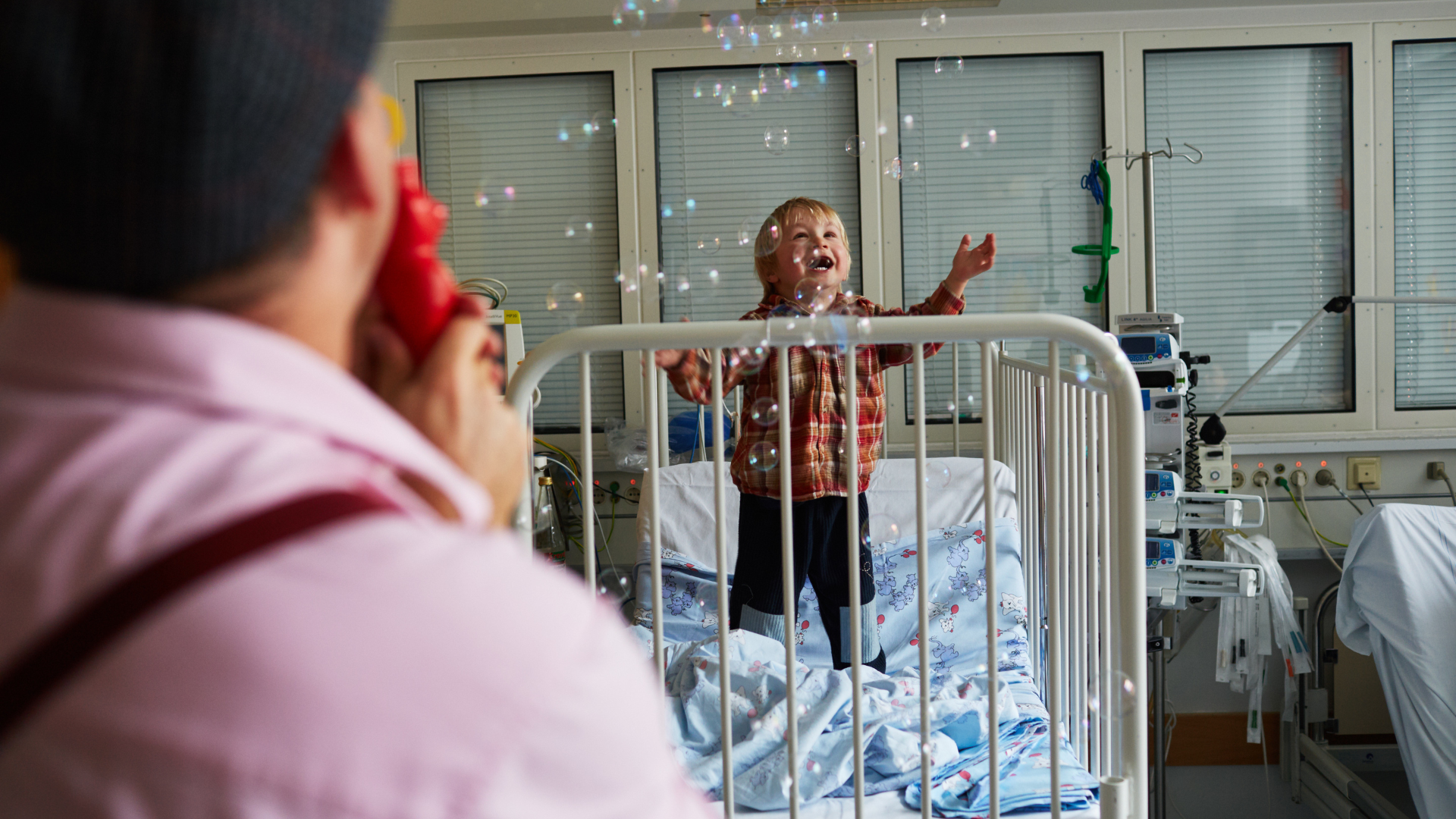 Clown bläst Seifenblasen für kleinen Jungen im Krankenhaus