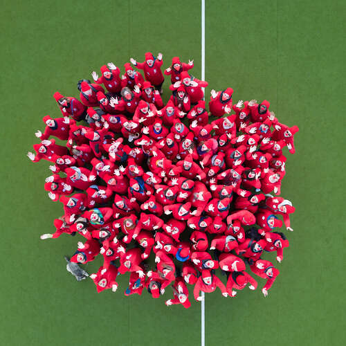 Menschen in Rot bilden eine riesige Clownnase auf einem Spielfeld