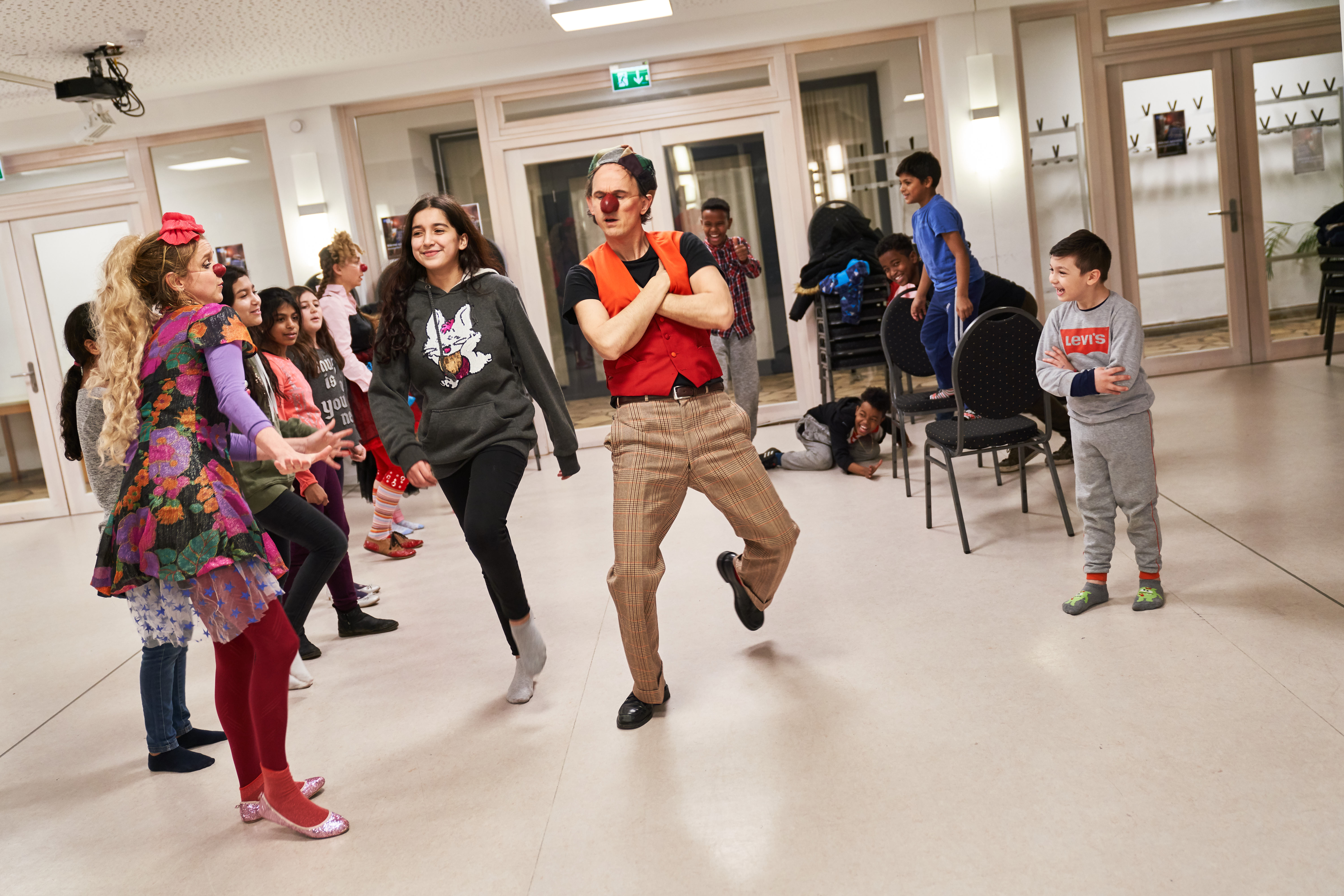Die Clowns spielen mit den Kindern in der Flüchtlings Einrichtung in einem Großen Raum 