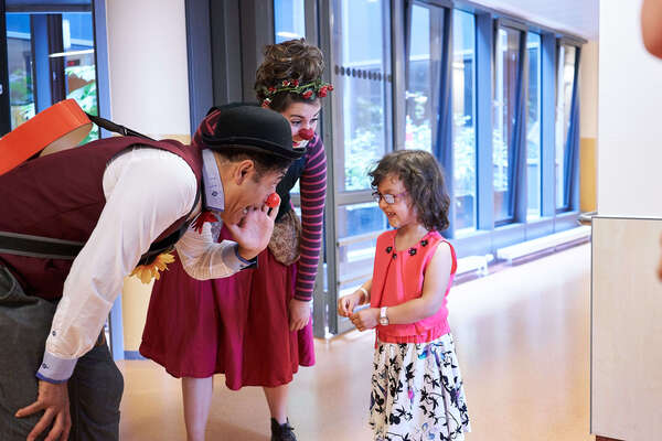Klinikclowns sprechen mit einem kleinem Mädchen auf den Krankenhaus Fluren 