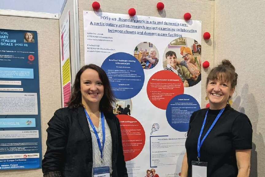 Zwei Frauen stehen vor einem Poster.