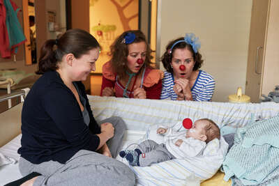 Klinikclowns machen ein kleines Baby glücklich und deren Mutter