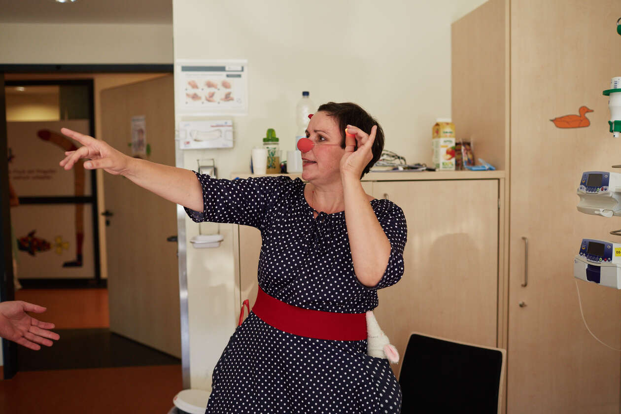 Ein weiblicher Clown tanzt im Krankenzimmer.