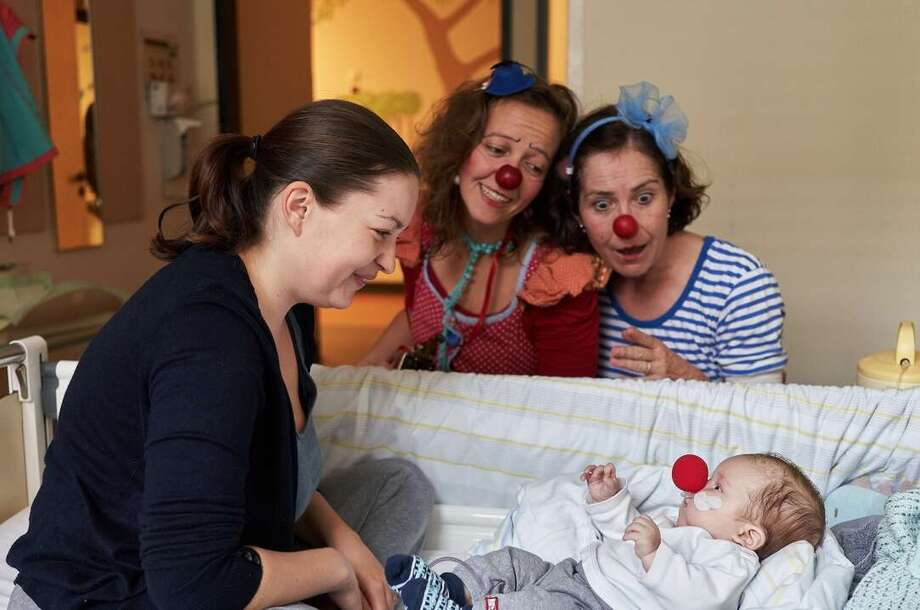 Ein_Weihnachtsengel_für_Jan(c)GregorZielke Zwei Clowns und eine junge Mutter schauen auf ein Baby mit einer roten Nasen im Krankenbett herab