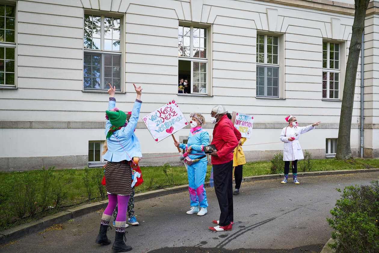ROTE NASEN Clownparade zum fünfzehnjährigen Geburtstag der Klinikclowns im Deutwschen Herzzentrum Berlin. Ein Kind schaut aus dem Fenster der Kinderkardiologie auf die Clowns.
