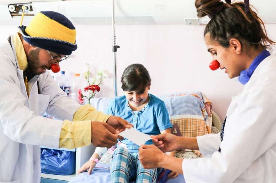 Zwei Clowns zeigen einem Kind in seinem Krankenhausbett einer ihrer Tricks 