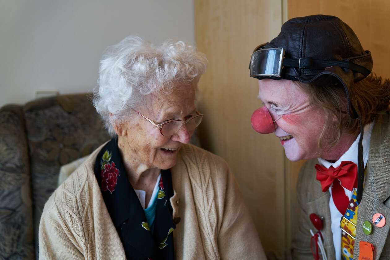 Ein Clown macht Quatsch mit einer Lachenden älteren Dame 
