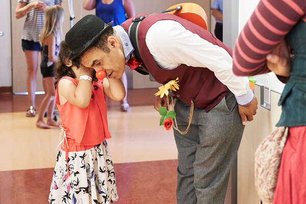 Mädchen flüstert einem Clown etwas ins Ohr.