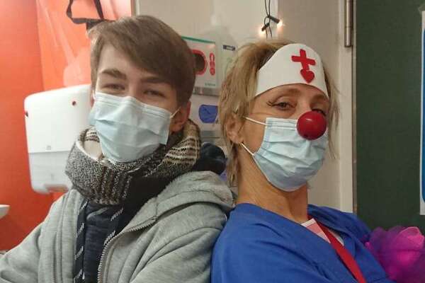 ein Clown und ein Jungendlicher stehen Rücken an Rücken und schauen in die Kamera