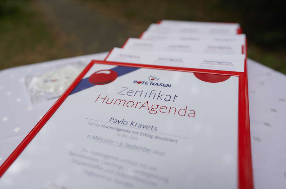 Ausdrucke der Zertifikte der ROTE NASEN HumorAgenten liegen auf einem Tisch.