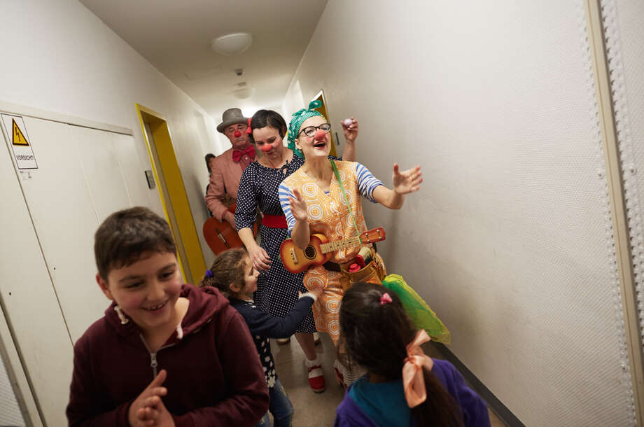 Die Clowns Laufen durch einen gang der Flüchtlingsunterkunft mit den Kindern voran 