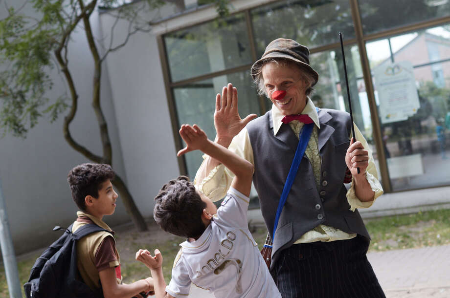 Der Clown Filou gibt einem Jungen in einem Flüchtlingheim einen Handschlag 