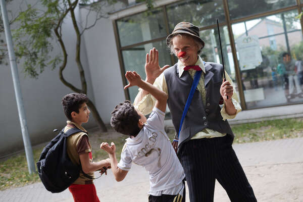 Der Clown Filou gibt einem Jungen in einem Flüchtlingheim einen Handschlag 
