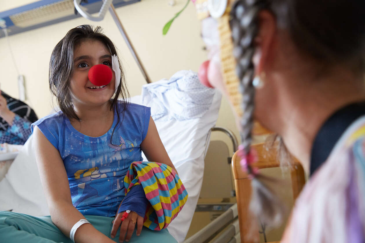 Ein Mädchen hat in ihrem Krankenbett eine rote Nase auf