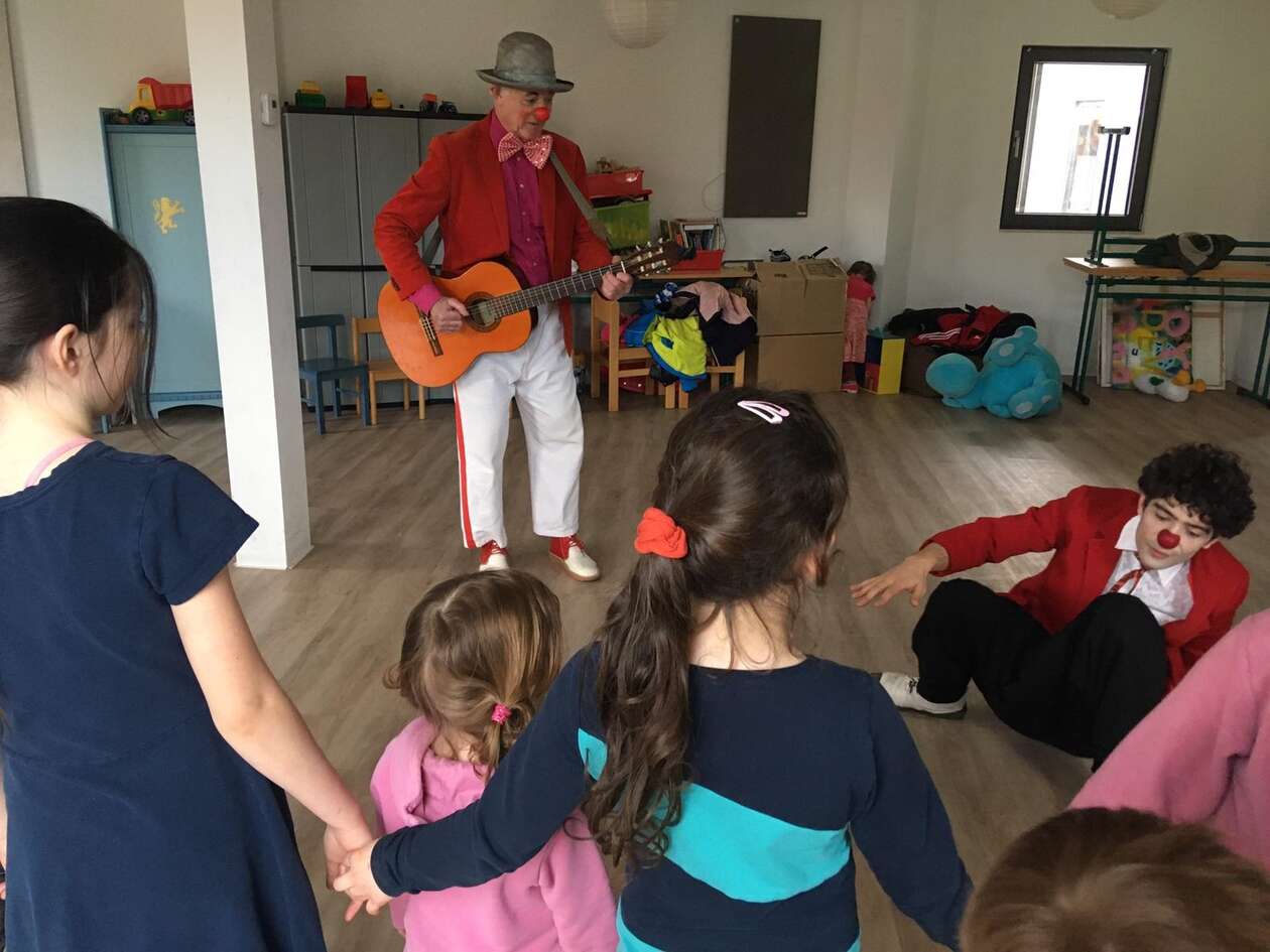 Zwei Clowns machen Musik und tanzen vor einer Gruppe von drei kleinen Mädchen