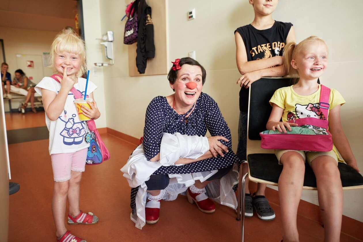 Die Clownin Nina hockt in der Mitte von drei jungen Mädchen und lacht
