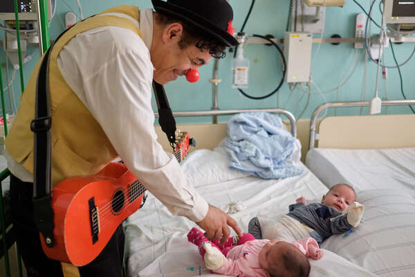 ROTE NASEN Klinikclown scherzt mit zwei Babys, die auf einem Krankenhausbett liegen. 