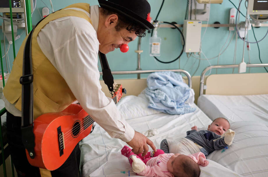 ROTE NASEN Klinikclown scherzt mit zwei Babys, die auf einem Krankenhausbett liegen. 