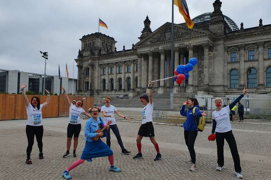 Eine Gruppe von Läuferinnen und zwei Clowns stehen vor dem Reichstag und jubeln. 
