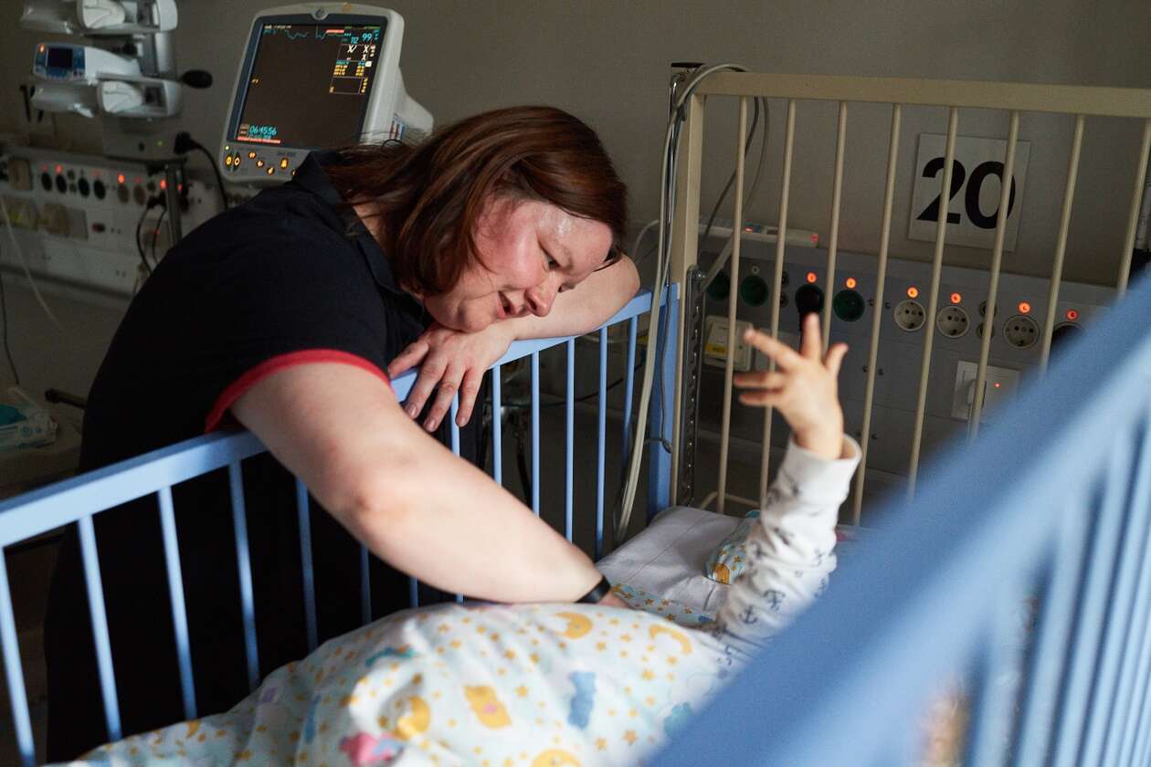 Eine Mutter und ihr kleines Kind im Deutschen Herrzentrum Berlin. Die Mutter streichelt ihr Kleinkind, das im Bett liegt