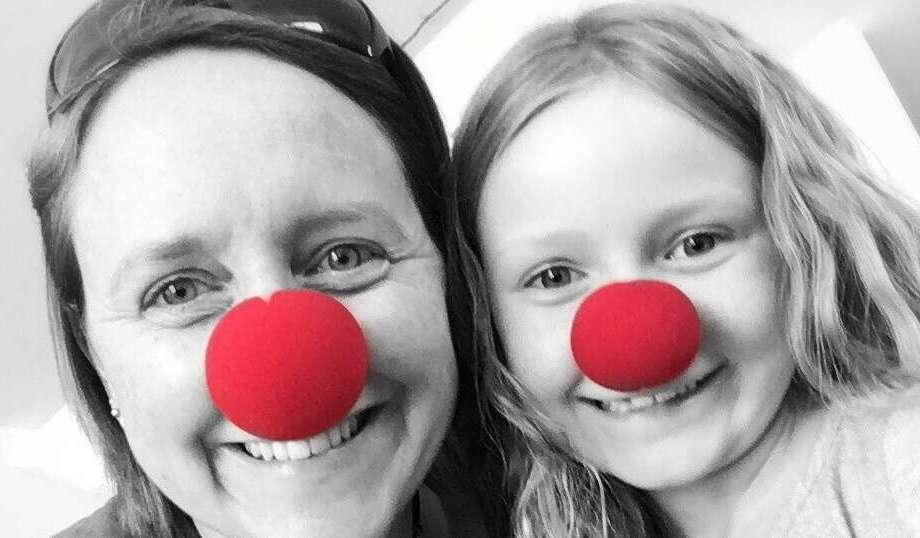 Die Familie macht ein Foto, wo Mutter, Tochter und das Kuscheltier drauf zu sehen ist. Alle haben rote nasen auf.