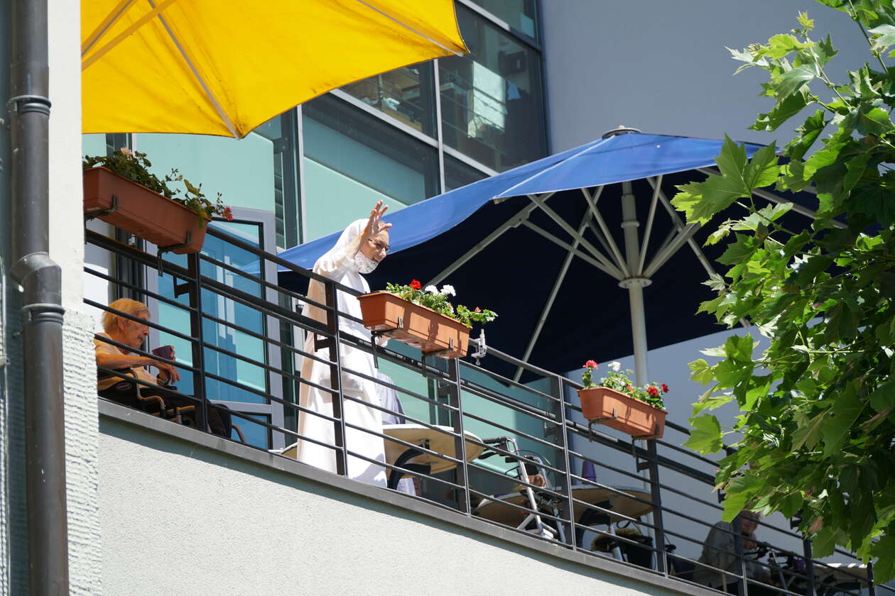 eine Frau im Nonnengewand steht auf dem Balkon und schaut herunter
