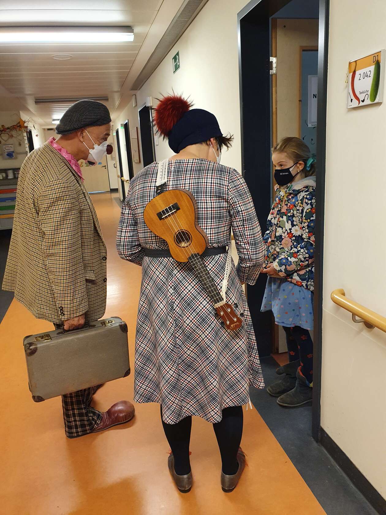 2 Clowns stehen im Krankenhaus vor der Tür der Patientin für den Besuch