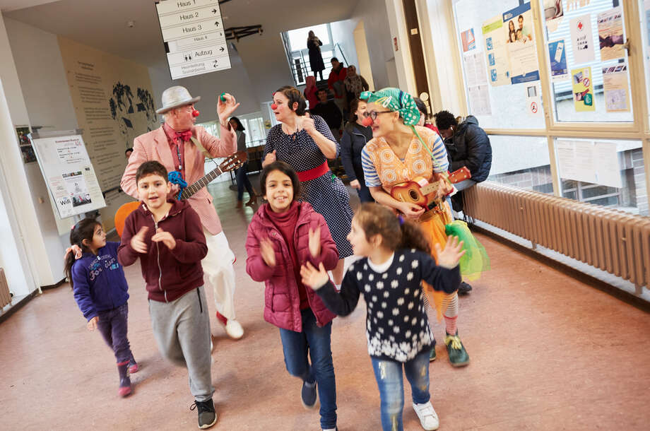 Die Clowns hüpfen fröhlich mit den Kindern durch die Fluchtlingsunterkunft
