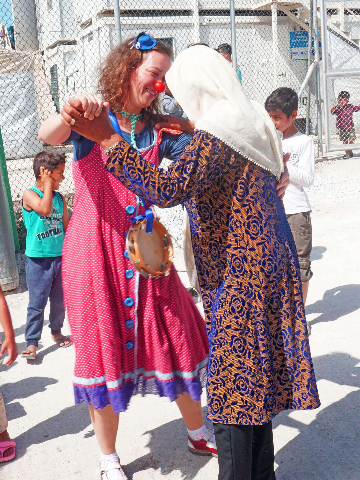 ROTE NASEN Clown Luciana tanzt mit einer Frau mit Kopftuch in einem Camp für refugees in Lesbos Griechenland im Rahmen des Emergency Smile Programmes