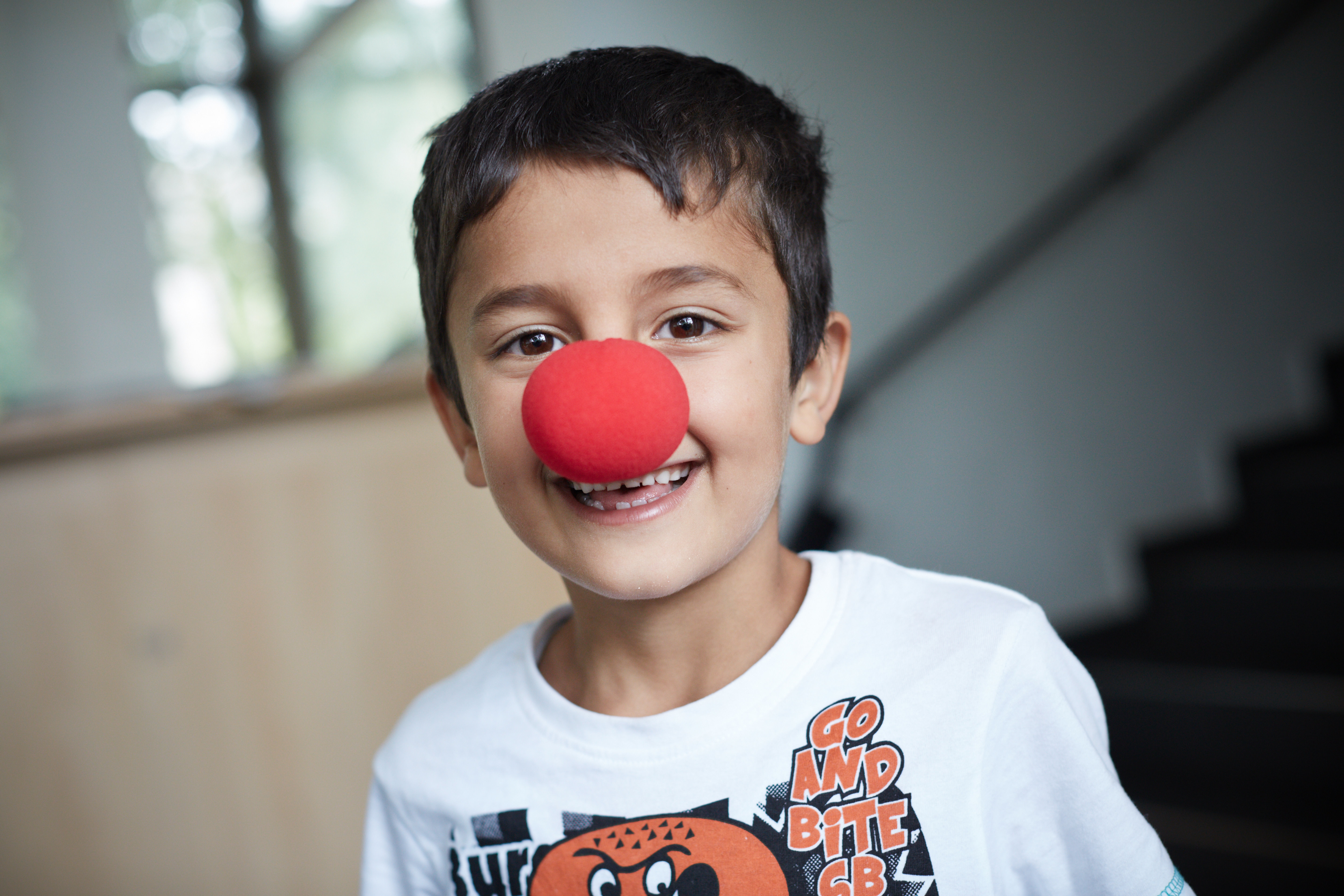 Ein Junge grinst mit einer roten Nase in einem Flüchtlingheim in die Kamara