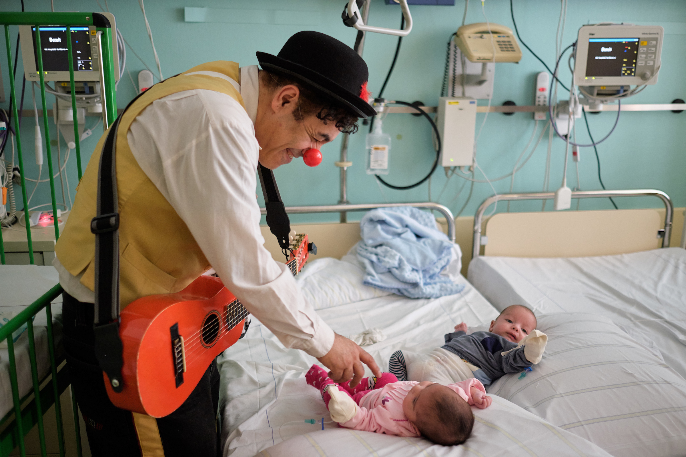 ROTE NASEN Klinikclown scherzt mit zwei Babys, die auf einem Krankenhausbett liegen. 