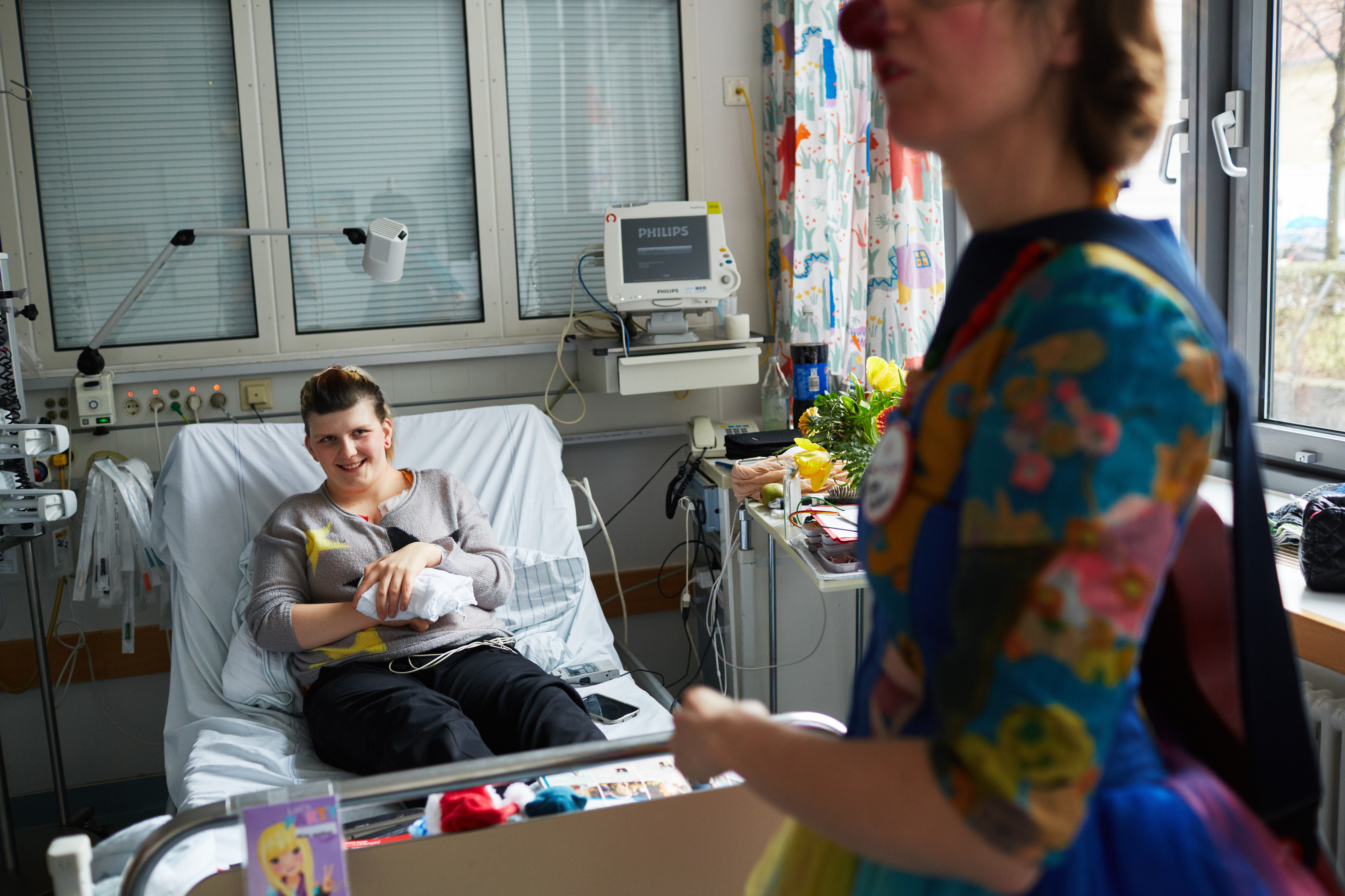 Eine lächelnde Jugendliche sitzt im Krankenbett.