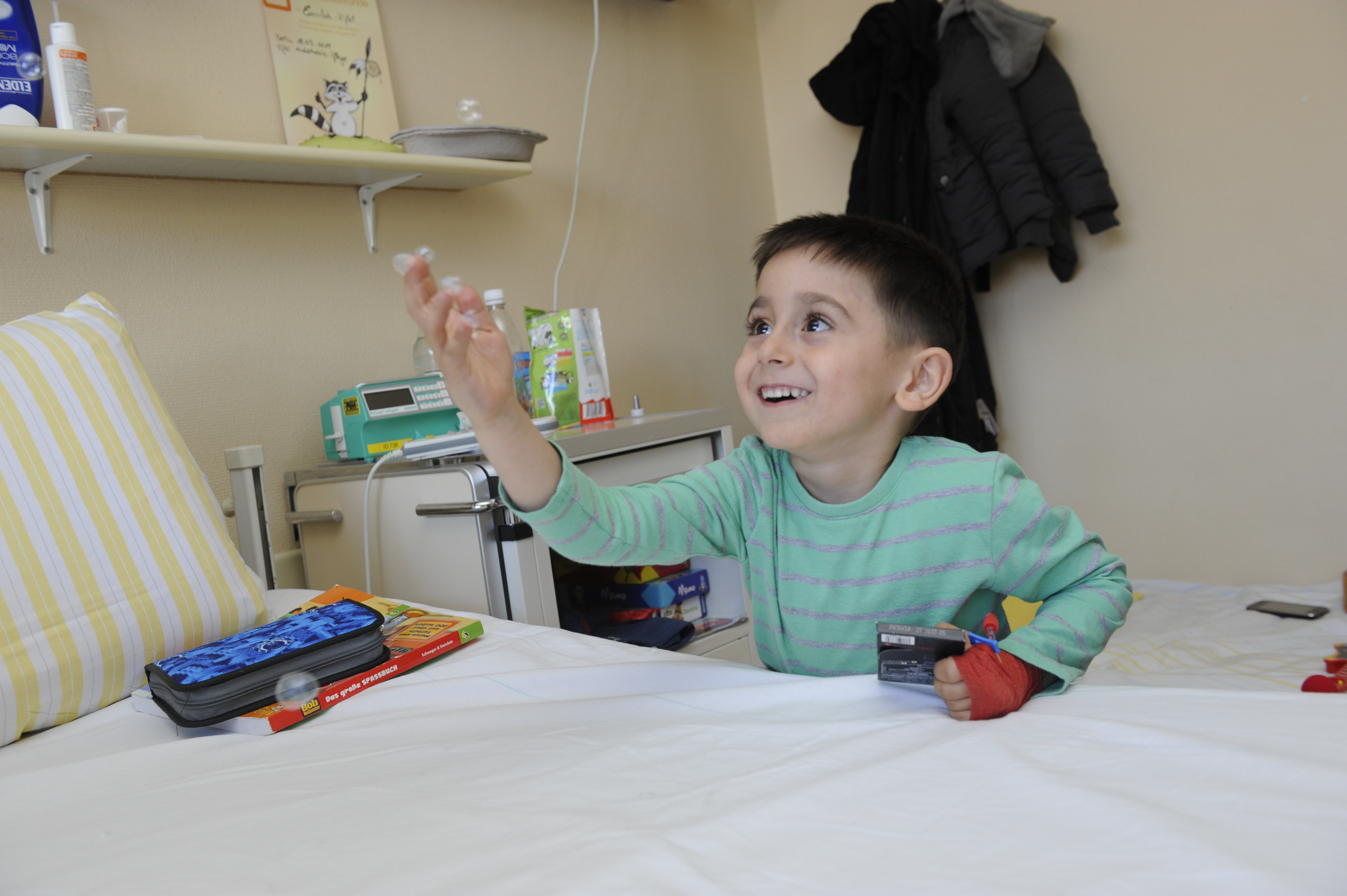 Ein kleiner Junge schaut lächelnd seinem Arm hinterher.