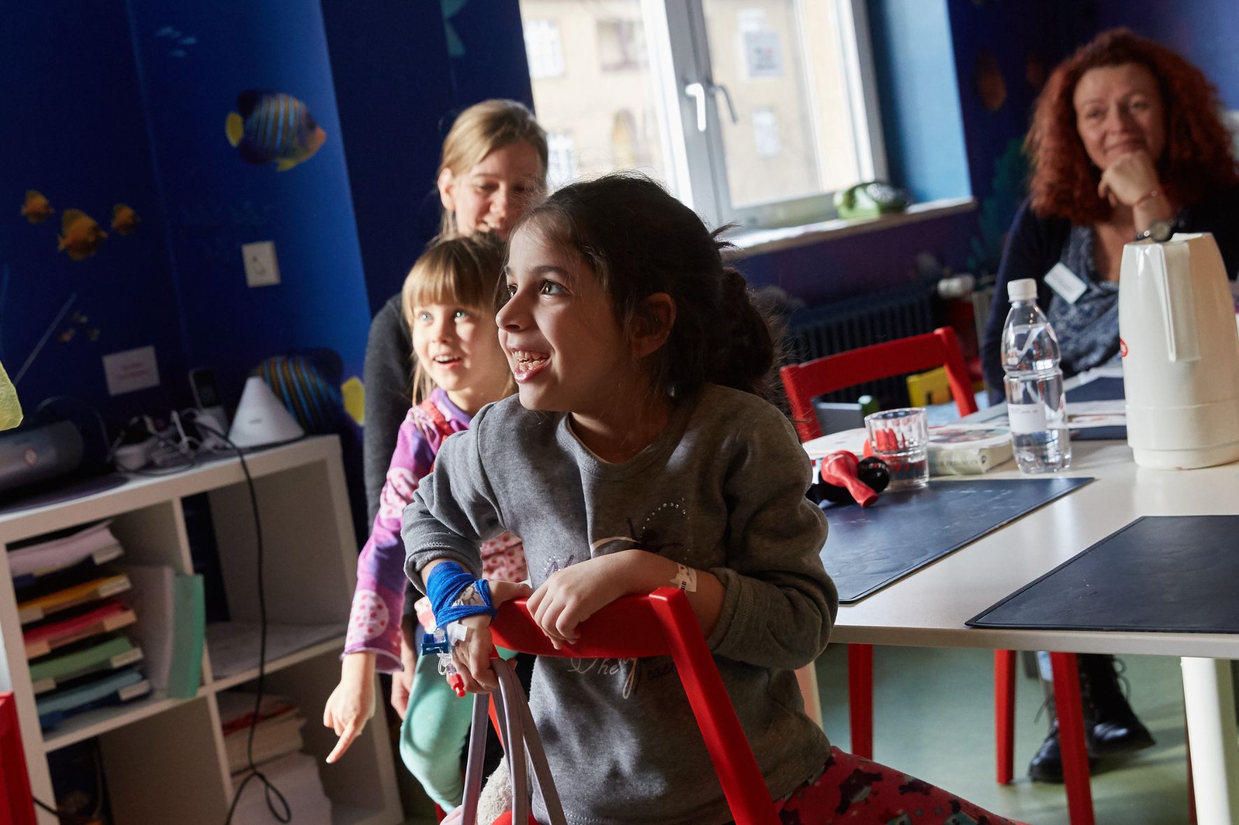Zwei Mädchen und ihre Mütter lachen über die ROTE NASEN Clowns.