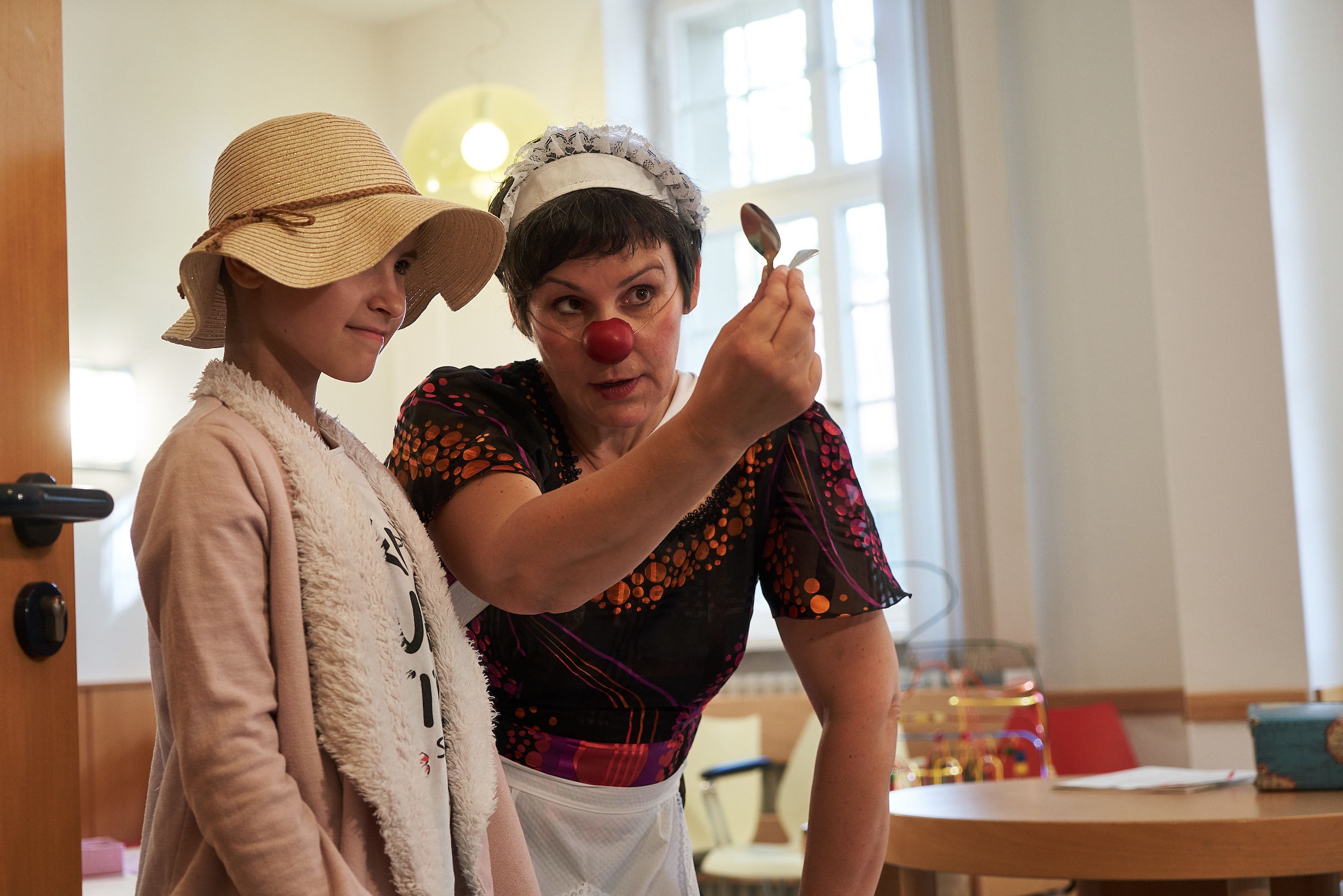 Der Clown Nina zeigt einem kleinem Mädchen einen Trick mit ihrem zauber Löffel 