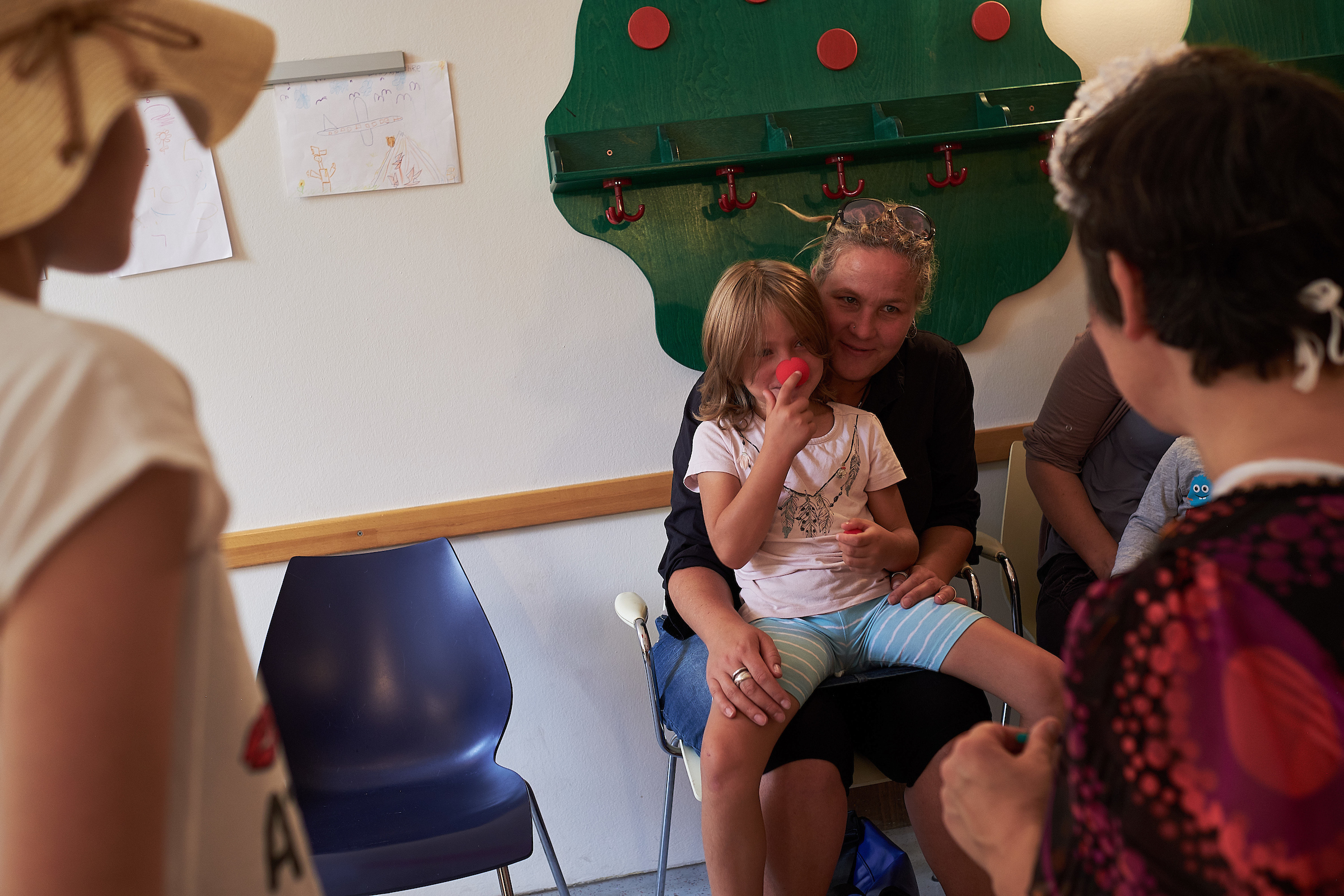 Ein Mädchen sietzt auf dem Schoß von ihrer Mutter und schaut die Clowns gestannt an 