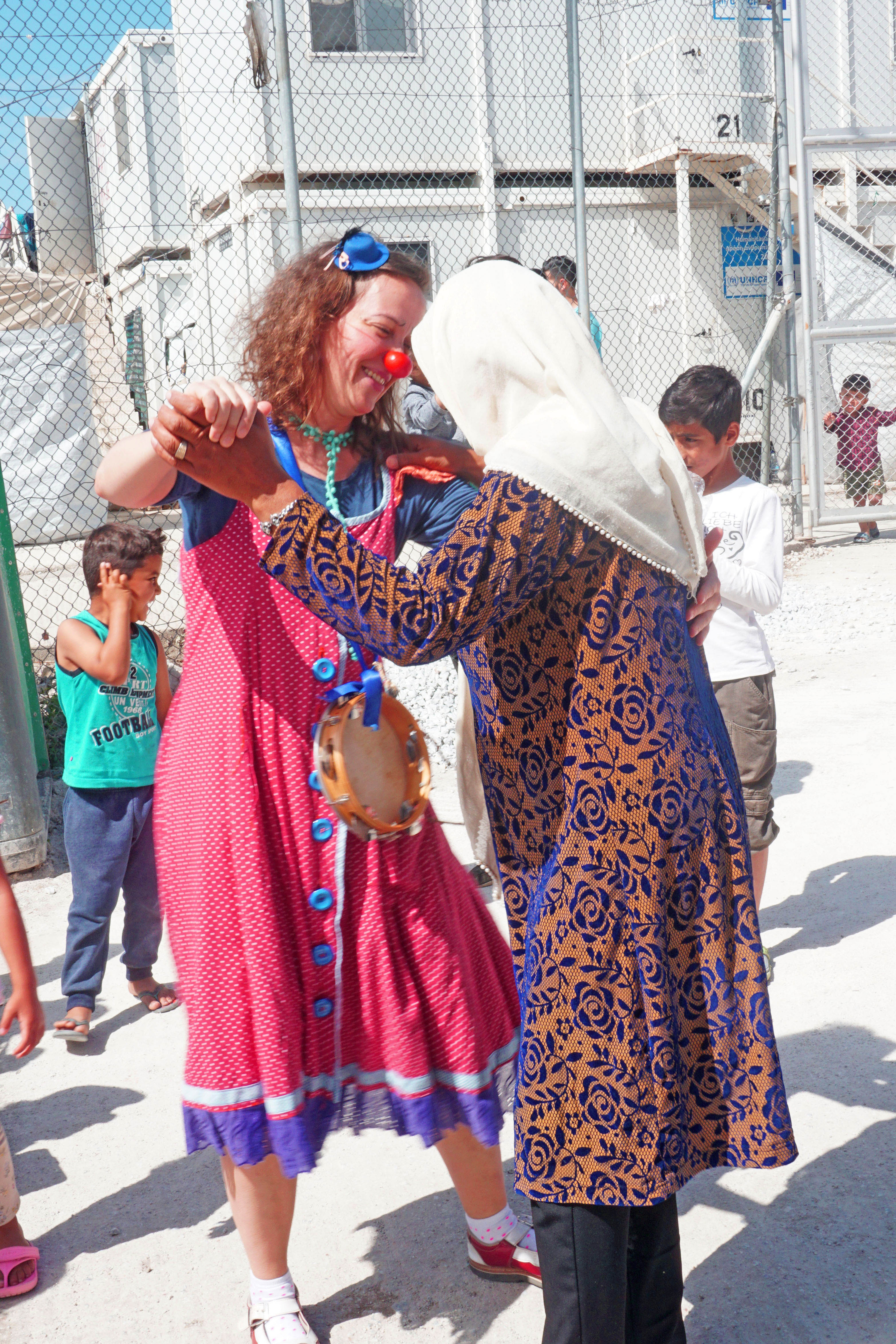 ROTE NASEN Clown Luciana tanzt mit einer Frau mit Kopftuch in einem Camp für refugees in Lesbos Griechenland im Rahmen des Emergency Smile Programmes