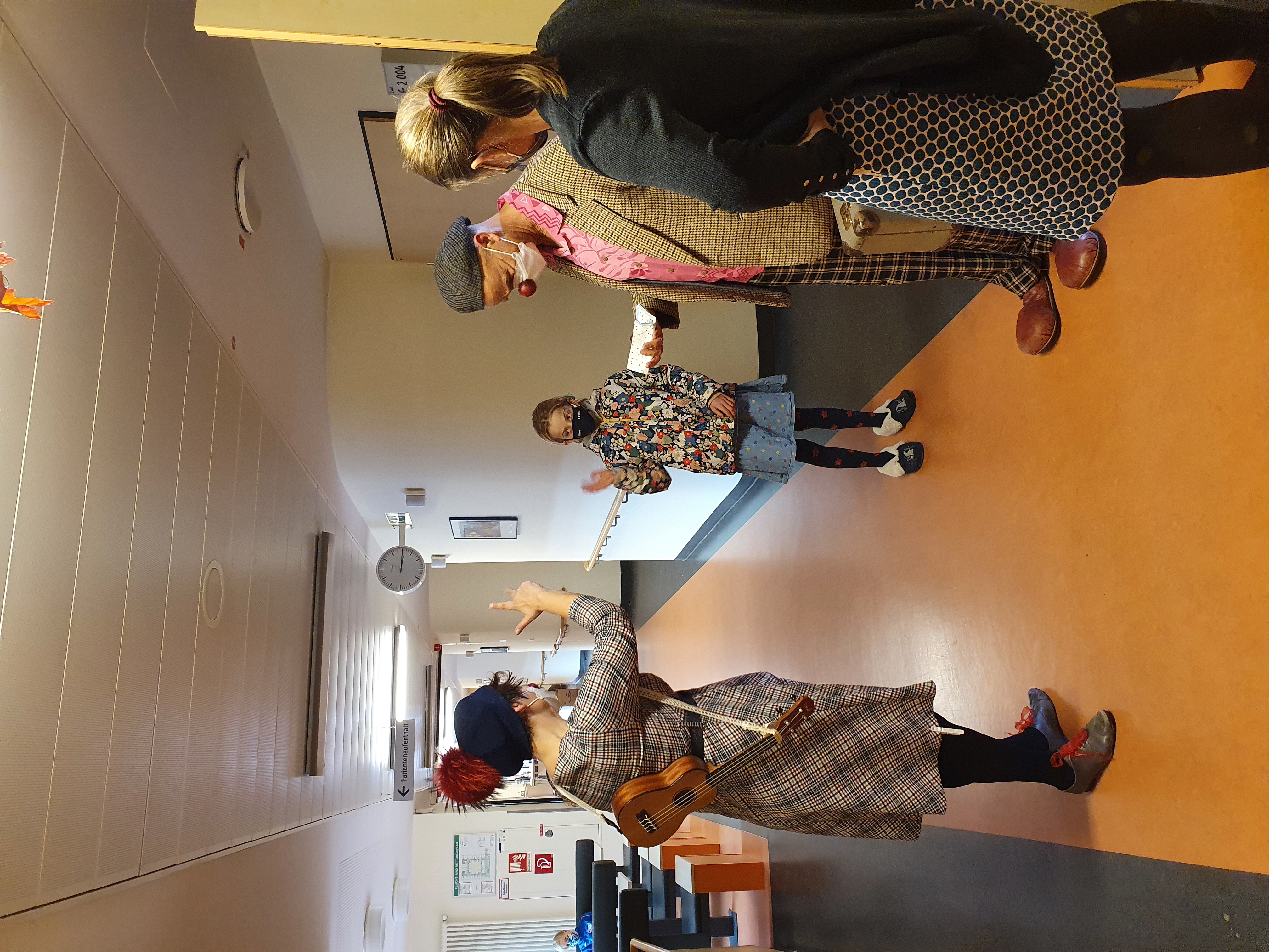 2 Clowns stehen mit einer Patientin und ihrer Mutter auf dem Flur im Krankenhaus nach einer Clownvisite