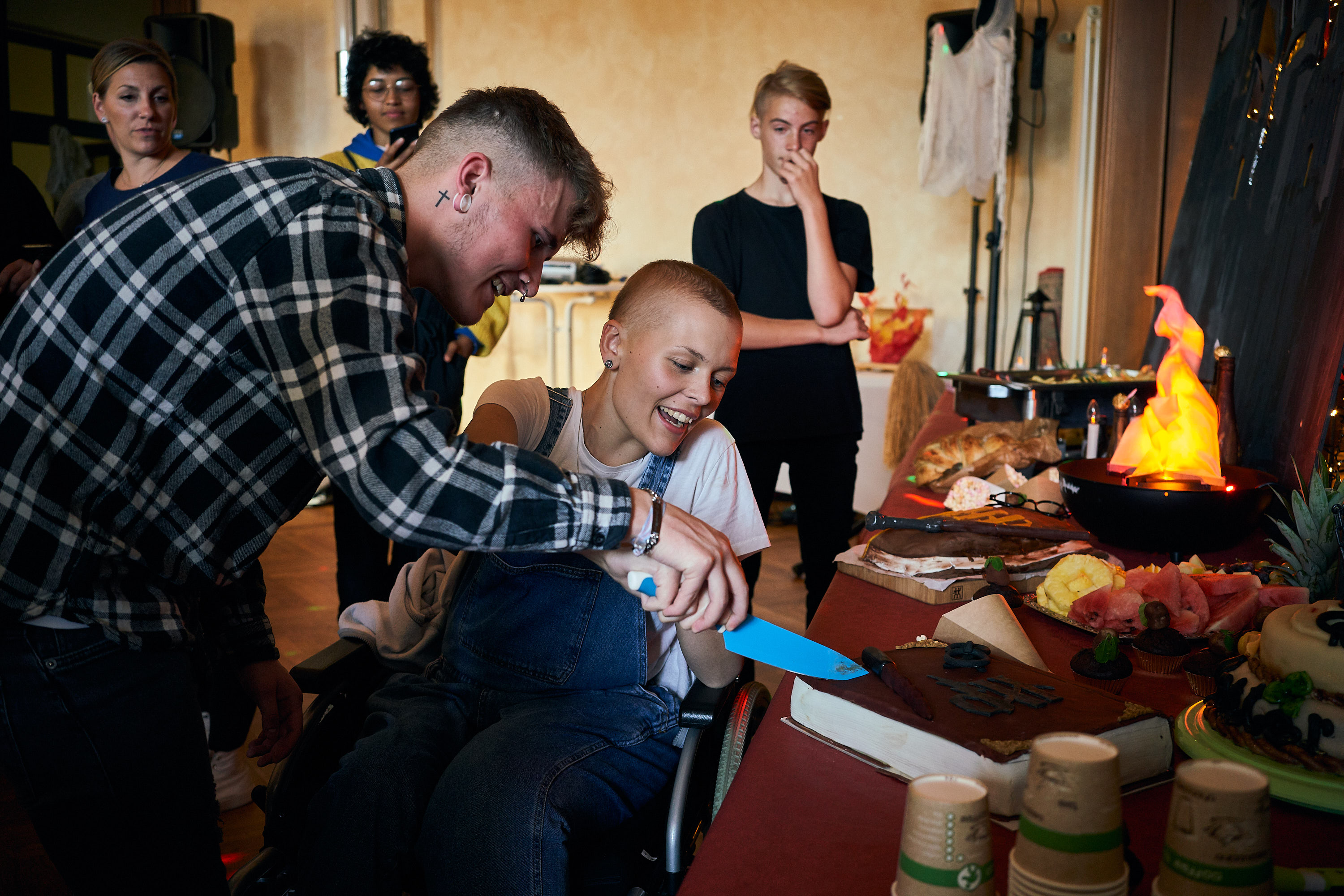 Zwei Personen schneiden einen Geburtstagskuchen an.