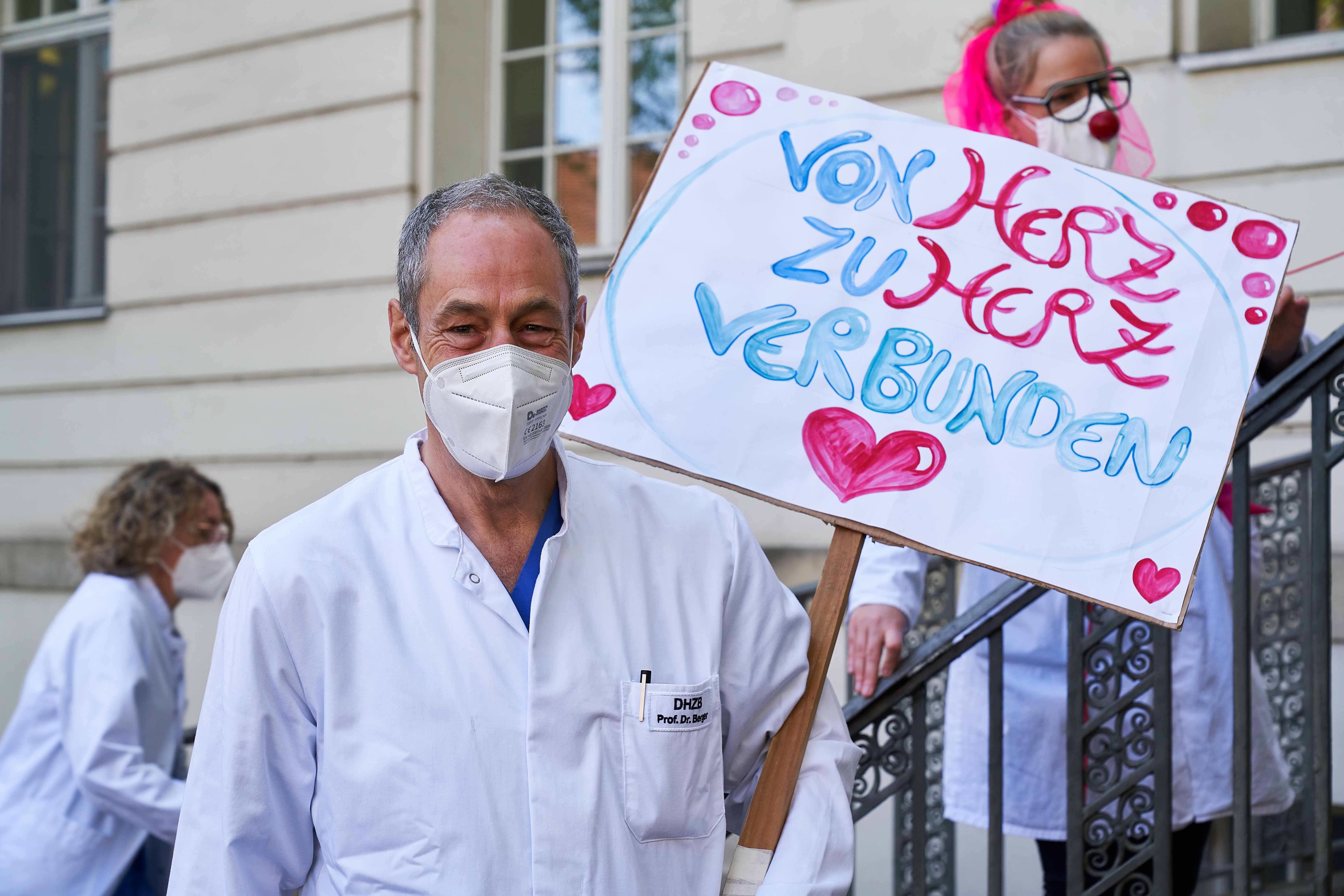 Professor Doktor Felix Berger, Direktor der Klinik für angeborene Herzfehler am Deutschen Herzzentrum Berlin, mit Schild zur Jubiläumsparade der Klinikclowns von Rote Nasen. Schrift auf dem schild: von Herz zu Herz verbunden.