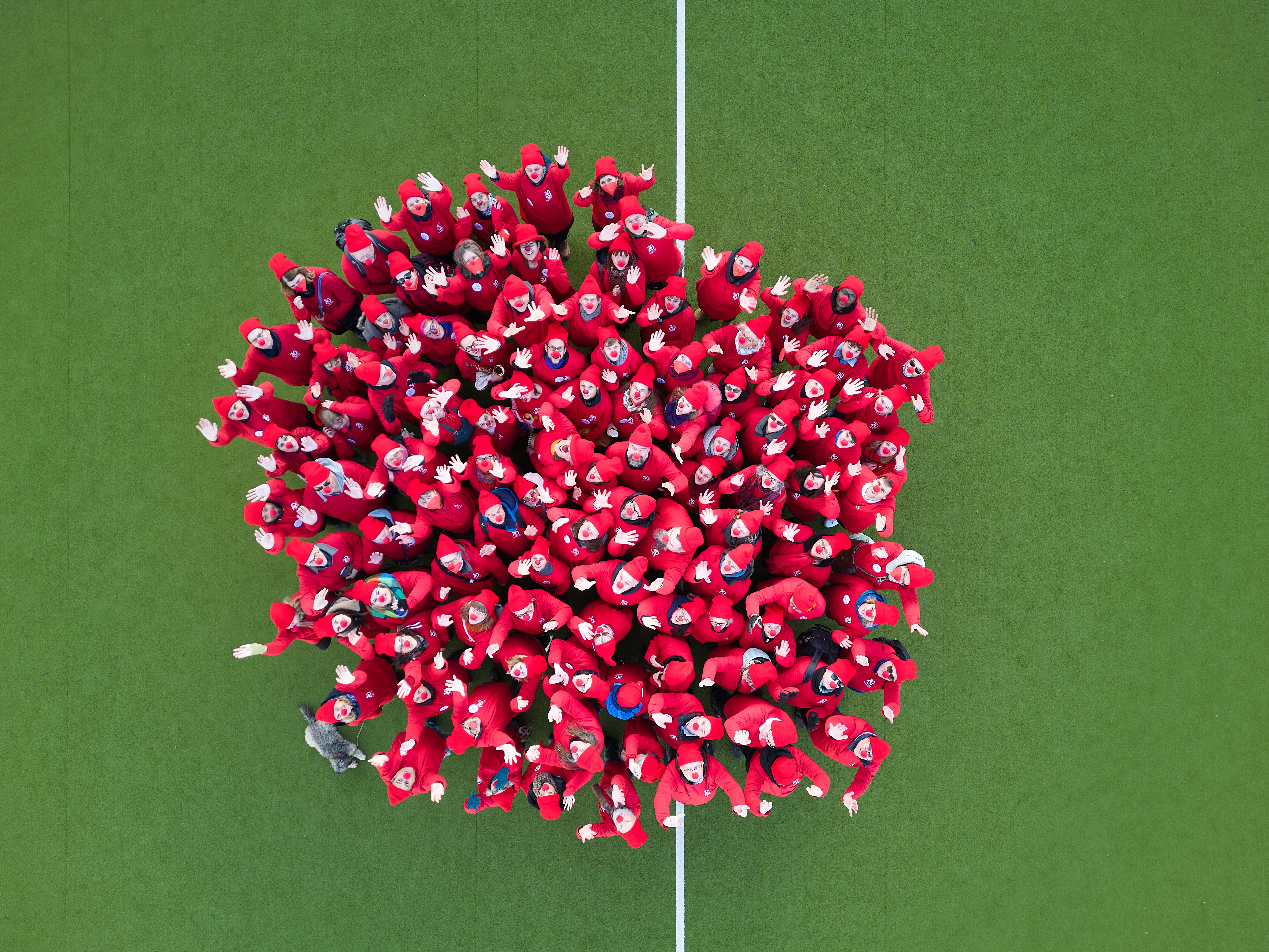 Menschen in Rot bilden eine riesige Clownnase auf einem Spielfeld