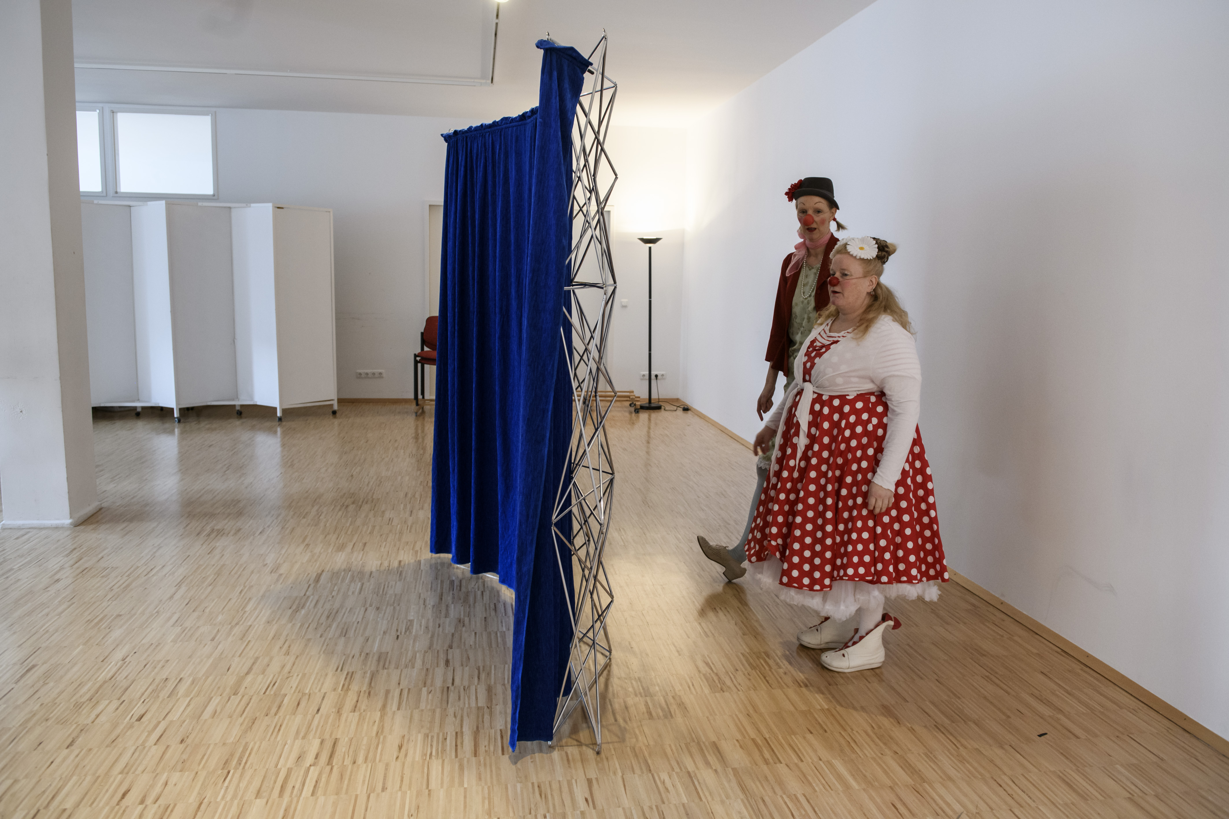 Zwei Clowns stehen hinter einem Raum trenner 