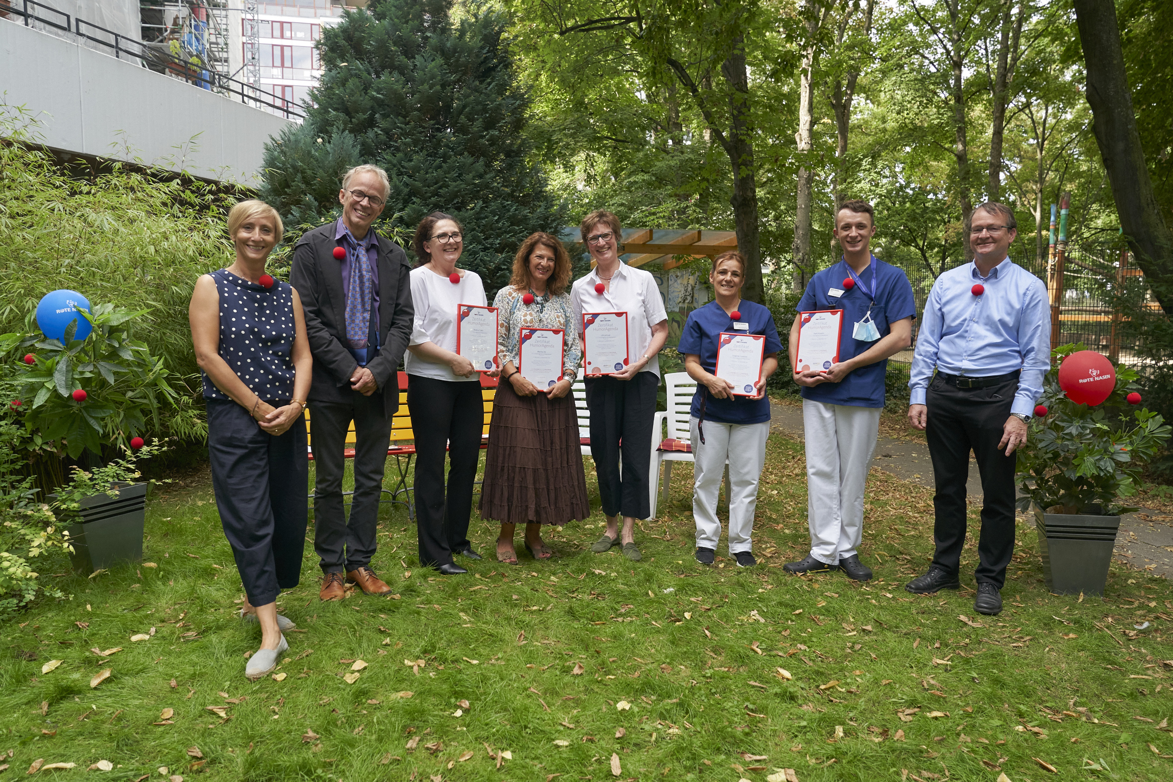 Vertreter von ROTE NASEN, der BAHN BKK und HumorAgenten bei der Zertifizierung im Garten der Pflegeeinrichtung Anlagenring.