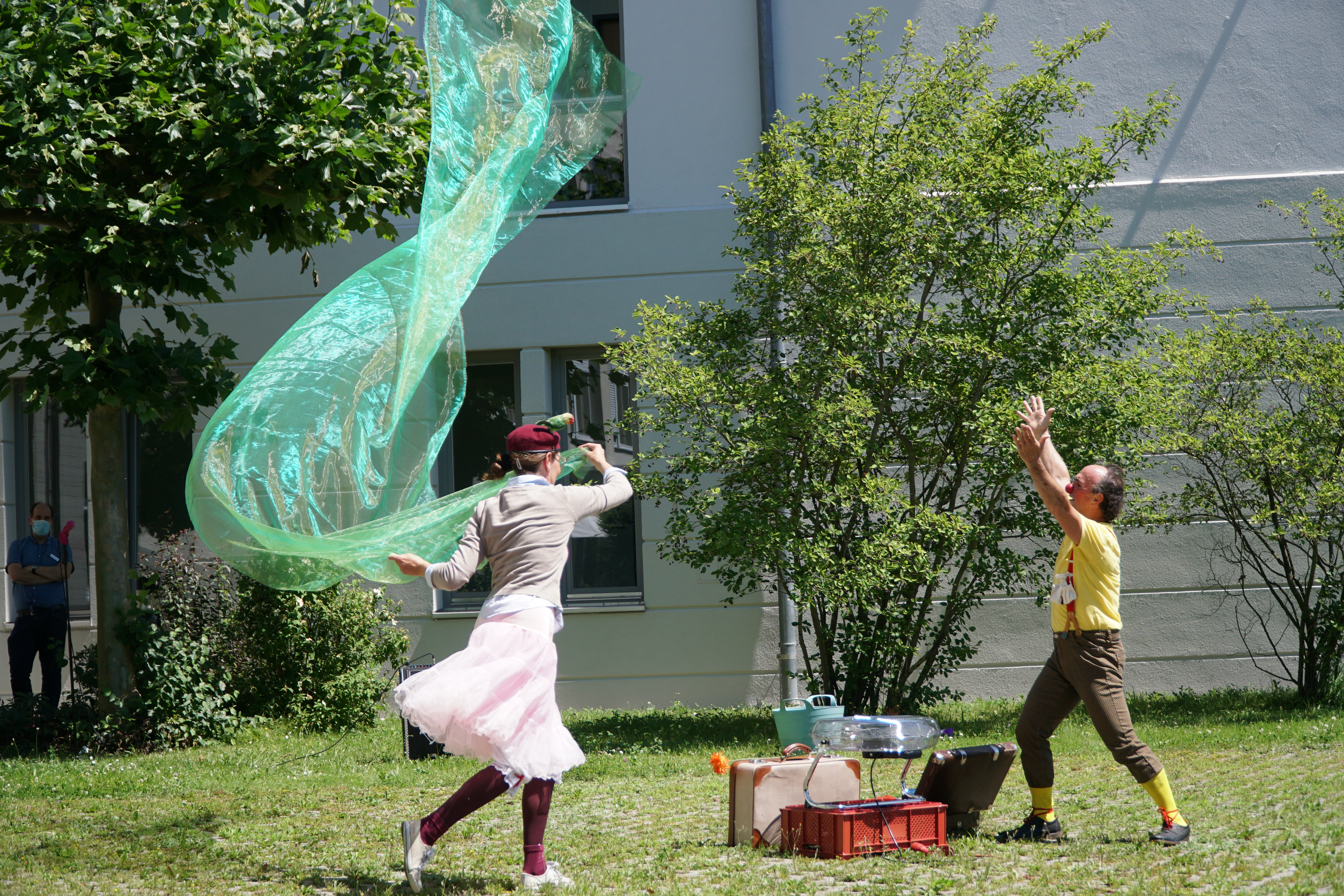 zwei Clowns tanzen im Hof mit Tüchern und machen Seifenblasen