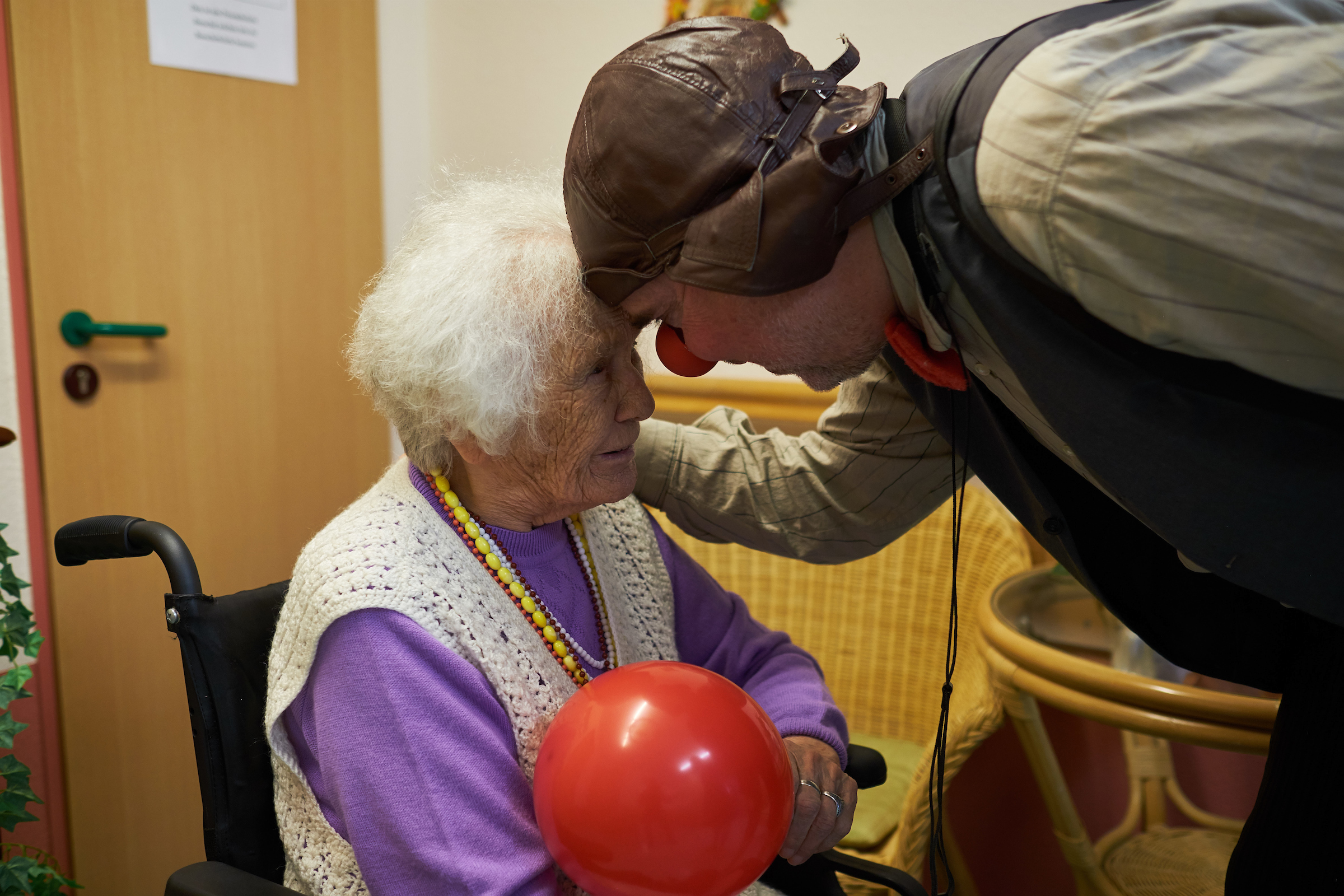 ROTE NASEN Klinikclown beugt sich zu lächelnder Seniorin. Fünf Clowntipps zum kreativen Umgang mit Demenz.