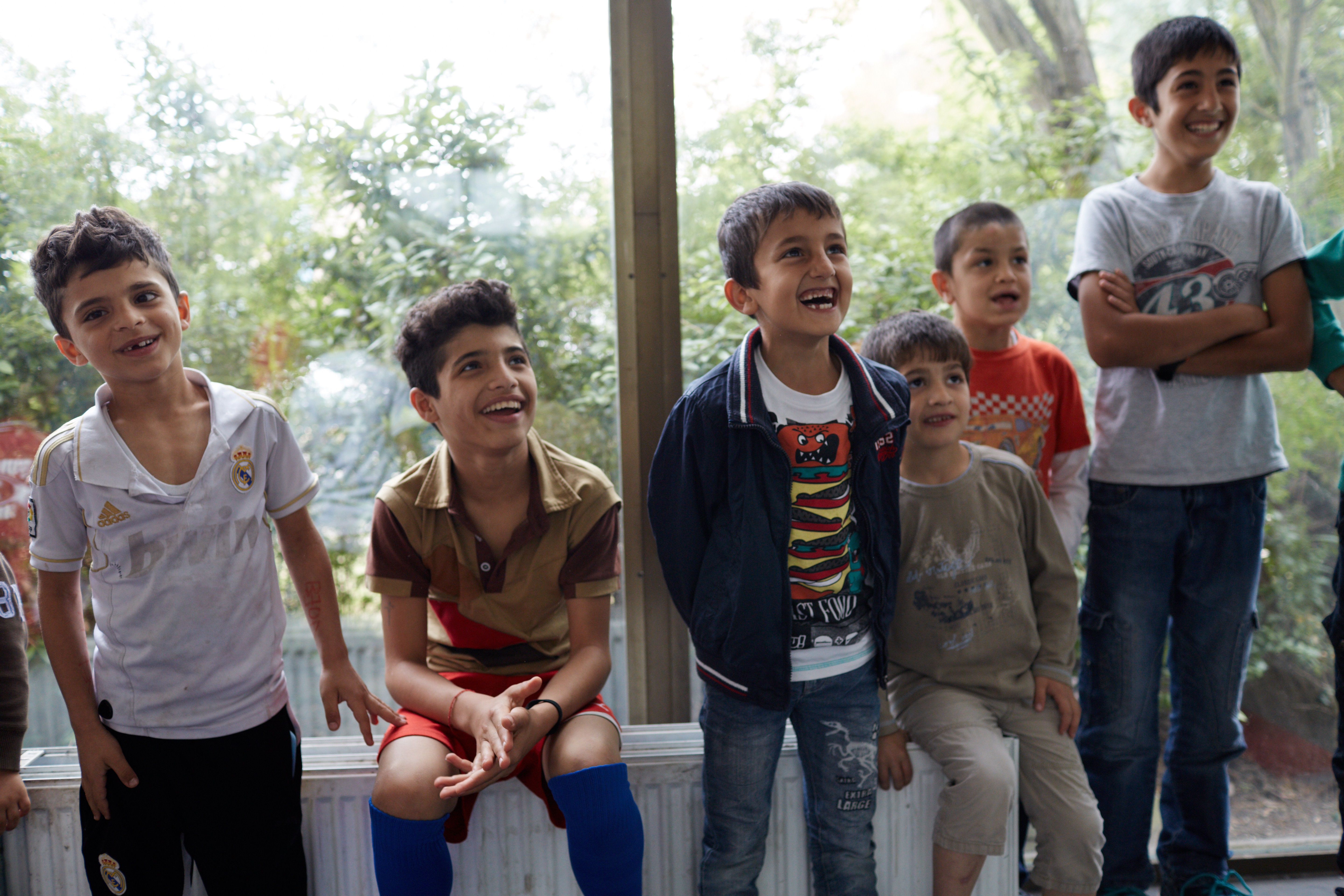 lachende kleine Jungs sitzen auf der Heizung schauen begeistert jemanden an