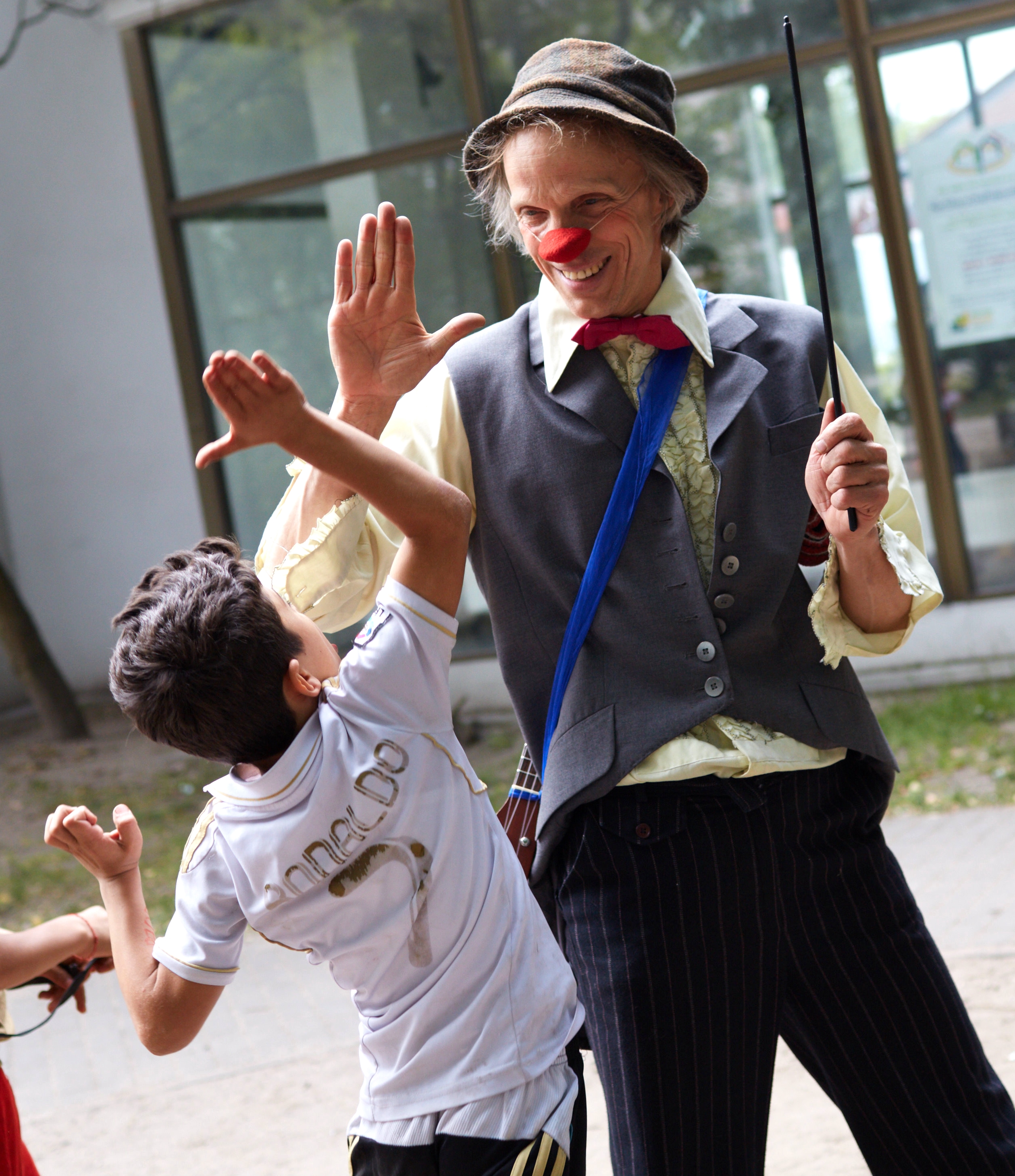 Der Clown Filou gibt einem Jungen in einem Flüchtlingheim einen Handschlag 